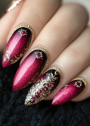 Luxurious stiletto nails with magenta gradient, gold designs, and gemstone accents for glamorous elegance.