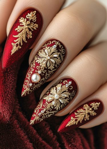 Exquisite luxury red nail art with gold filigree and pearl accents on almond-shaped nails.