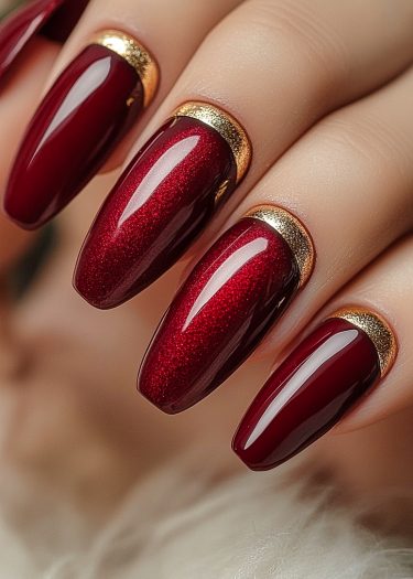 Elegant long almond-shaped red nails with gold accents for luxurious manicure perfection.