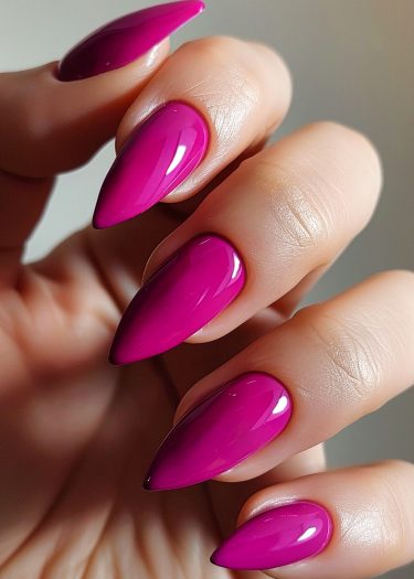 Vibrant fuchsia almond-shaped nails showcase elegant manicure artistry and stylish personal grooming.