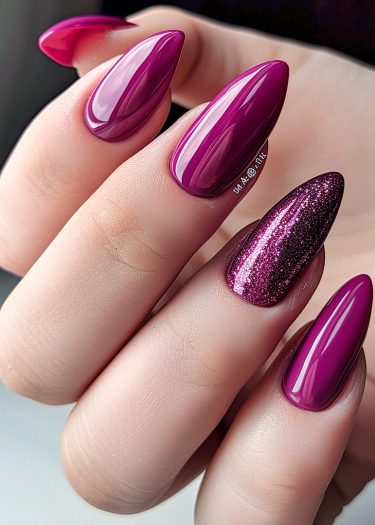 Chic magenta stiletto nails with glitter accent in a stylish, polished manicure.