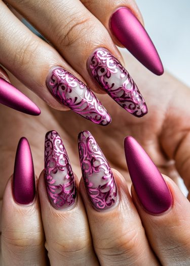 Elegant magenta almond-shaped nails with intricate filigree design and matte finish.