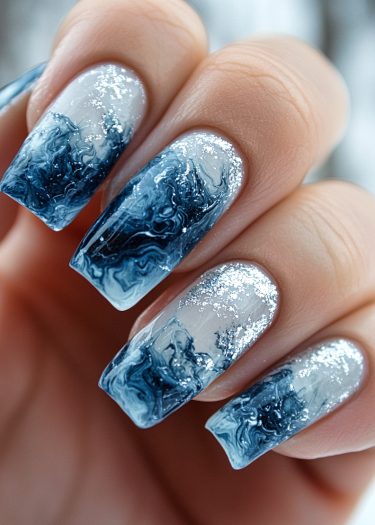 Elegant blue and white marbled nails with silver glitter resembling ocean waves design.