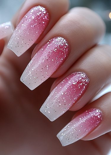 Elegant coffin-shaped ombré nails feature a pink gradient and sparkling glitter for a glamorous look.