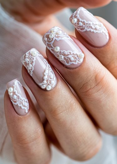 Elegant manicure featuring white lace design and pearls on soft pink nails.