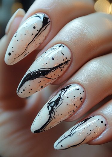 Elegant stiletto nails with artistic black designs and shimmering glitter on a light base.