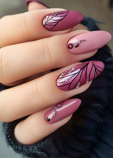 Elegant almond-shaped manicure with intricate leaf design and sparkling accents on muted pink nails.