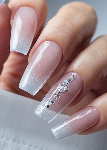 Elegant manicured coffin nails featuring ombre gradient and sparkling rhinestones for a luxurious look.