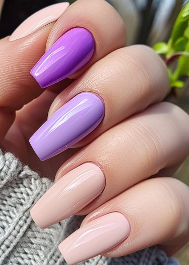 Elegant pastel nail design with purple accents on manicured hands against a cozy sweater background.