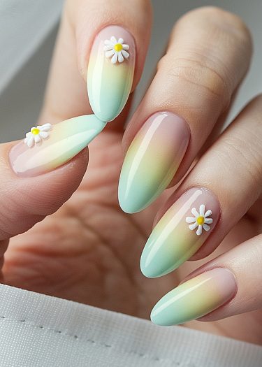 Elegant almond-shaped nails with pastel ombre and daisy designs for a charming manicure look.