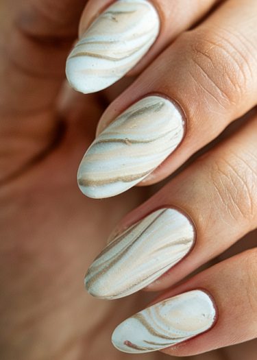 Elegant almond-shaped marble-effect nails in soft whites, beiges, and light blues.