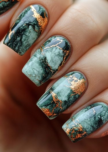 Elegant green marble nail design with gold accents for a luxurious and artistic look.