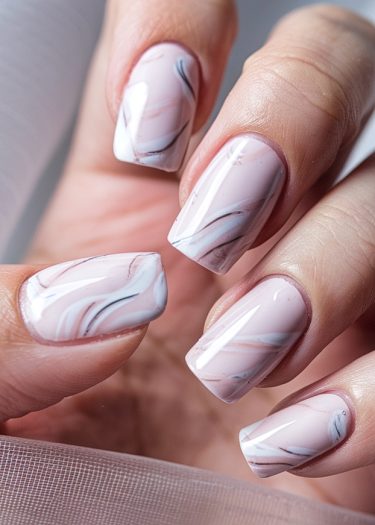 Elegant marble nail art in soft pink, white, and gray with a glossy finish.