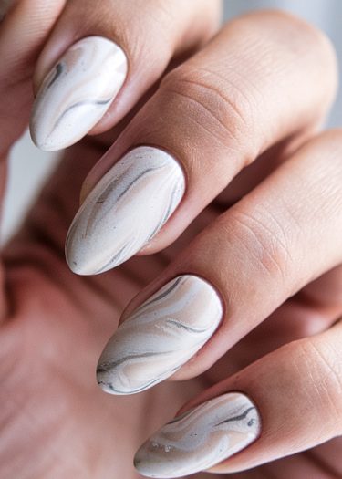 Elegant almond-shaped marble nail art in creamy white and soft gray tones.