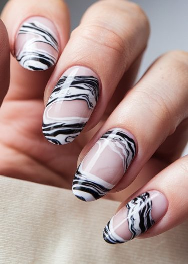 Elegant black and white marble almond nails showcasing intricate patterns and glossy finish.