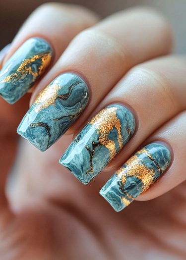 Elegant marbled blue-gray nails with gold accents for a chic, sophisticated manicure.