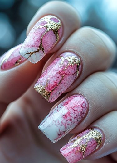 Elegant marbled pink and white nails with golden accents, showcasing sophisticated nail art design.