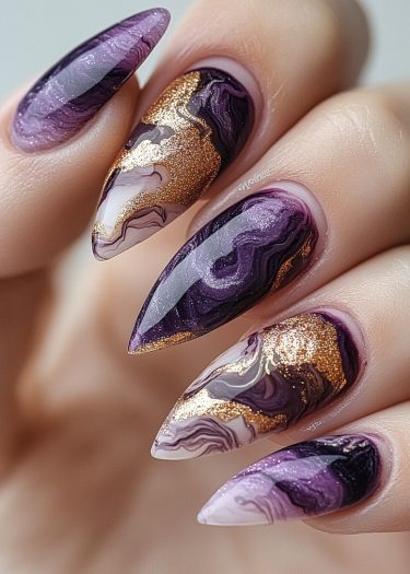 Elegant stiletto nails with marbled purple and black designs, adorned with luxurious gold accents.