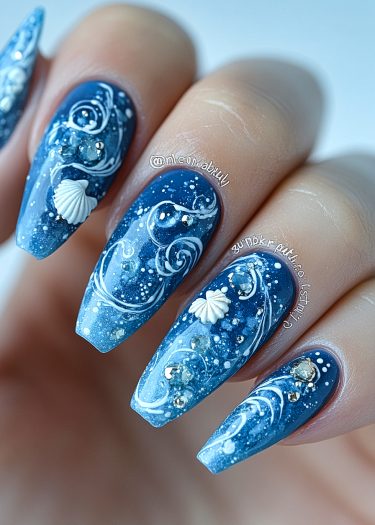 Artistic maritime nail design featuring ocean-inspired gradients, waves, seashells, and rhinestones.