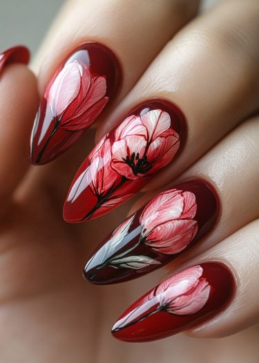 Elegant maroon nail art featuring intricate pink floral designs and a glossy finish.