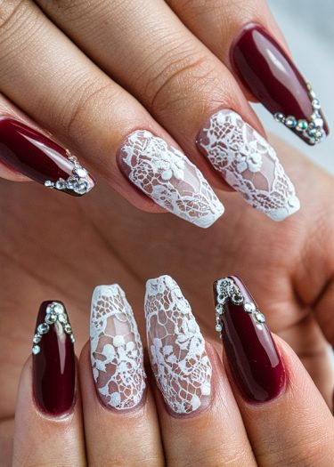 Elegant burgundy and lace nail art design with rhinestones for a luxurious manicure.