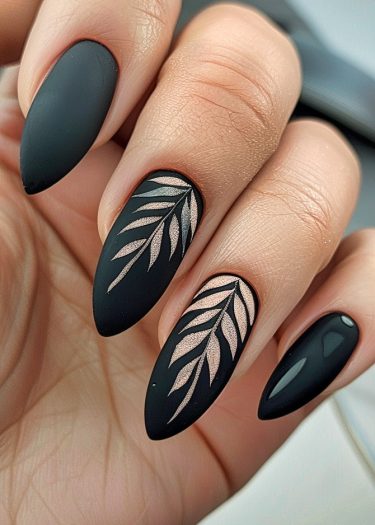 Elegant matte black almond nails with rose gold leaf designs for a chic manicure.