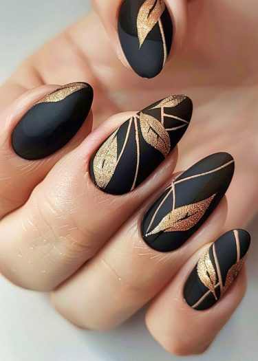 Elegant matte black and gold nail art with intricate designs on almond-shaped nails.