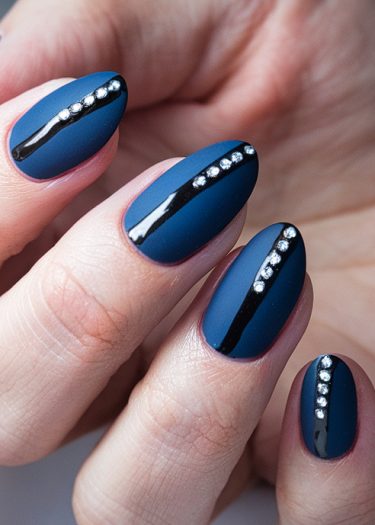 Elegant matte blue nails with black stripes and rhinestones for a chic manicure design.