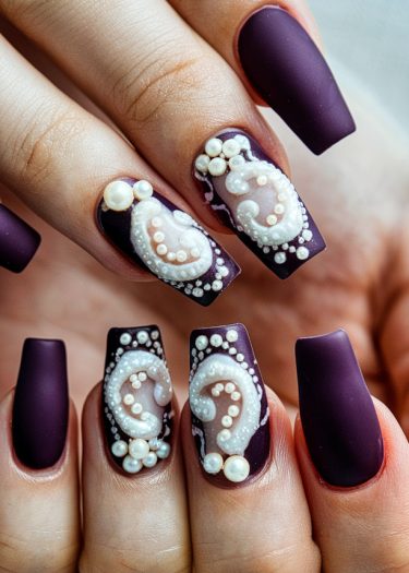 Elegant matte dark purple nails adorned with intricate white pearl designs and textures.