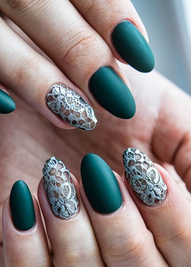 Elegant matte green nails with intricate white lace designs in a close-up view.