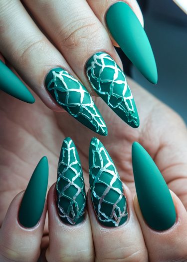 Elegant matte green stiletto nails with metallic diamond patterns for a luxurious manicure.