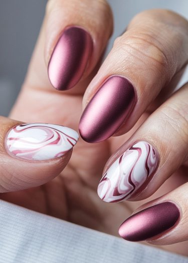 Elegant almond-shaped nails with matte burgundy and glossy marble designs for a stylish manicure.