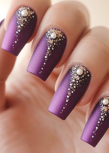 Elegant matte purple nail art with pearls and gold accents for a luxurious look.