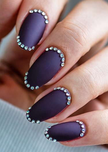 Elegant almond-shaped matte purple manicure with rhinestone accents for a sophisticated look.