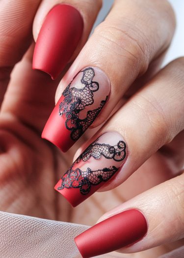 Elegant matte red coffin nails with intricate black lace designs for a sophisticated manicure.