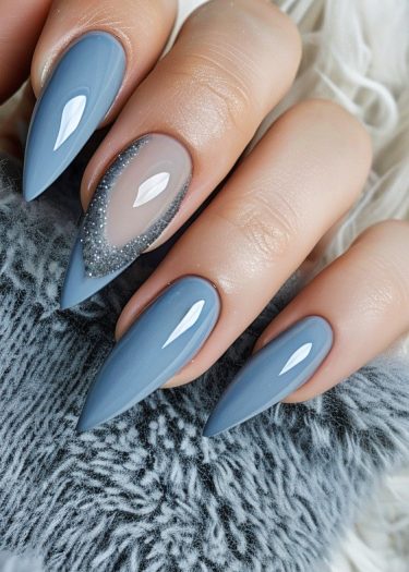 Elegant matte steel blue stiletto nails with shimmer accents against a cozy gray fabric.