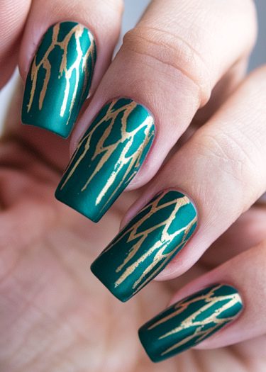 Stunning matte teal nail art with gold jagged designs for a stylish, modern look.