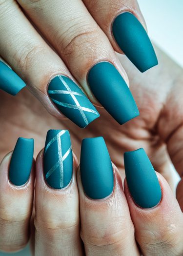 Stylish matte teal coffin nails with metallic silver accents for modern nail art.