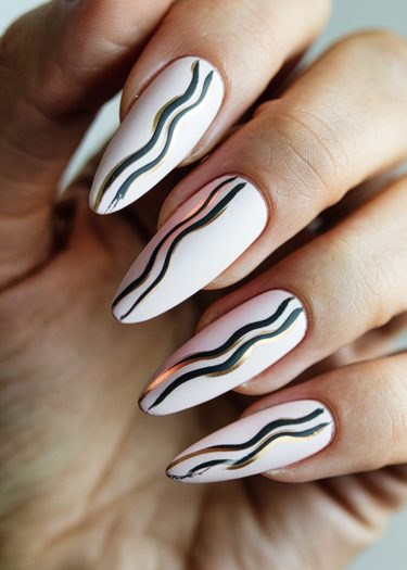 Elegant matte white nails with artistic black and gold designs for a sophisticated look.