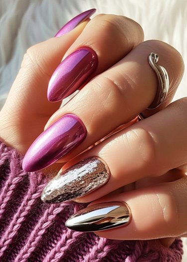 Glamorous metallic almond-shaped nails with vibrant designs and a cozy knitted wrist detail.