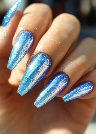 Stunning metallic blue stiletto nails with holographic accents for a glamorous manicure look.