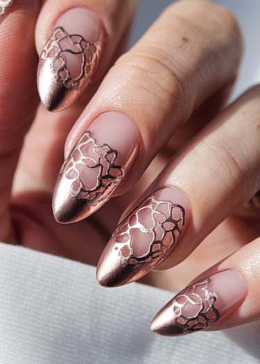 Elegant stiletto nails featuring matte pink-nude base and metallic rose gold lace design.