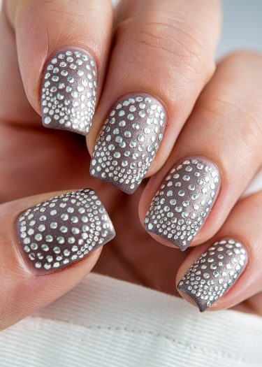 Elegant metallic silver nails with reflective embellishments showcase intricate nail art design.