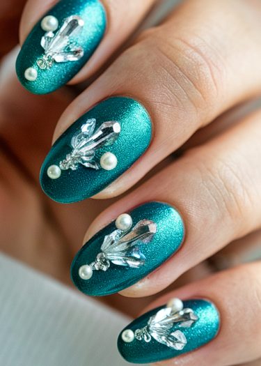 Luxurious metallic teal nails adorned with glitter and 3D embellishments for a stunning look.