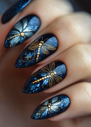 Elegant stiletto nails with metallic gold dragonflies on glossy midnight blue background.