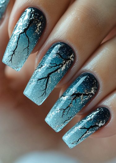 Stunning midnight blue gradient nails with delicate tree branch nail art and shimmering gold flakes.