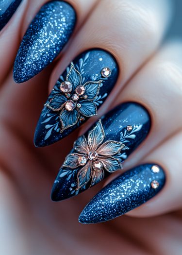 Elegant midnight blue nail art with glitter, floral designs, and rhinestones for a glamorous look.