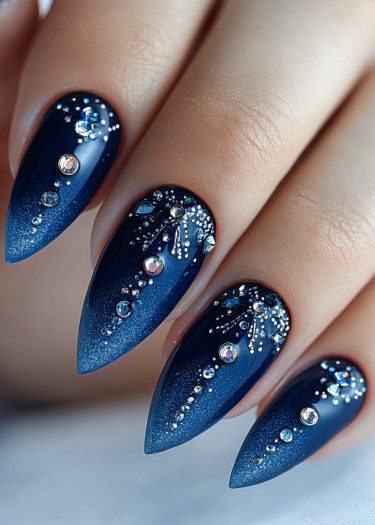 Elegant navy blue ombré stiletto nails adorned with shimmering rhinestones and silver glitter.