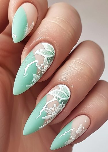 Elegant mint green floral nail art with intricate designs on manicured almond-shaped nails.