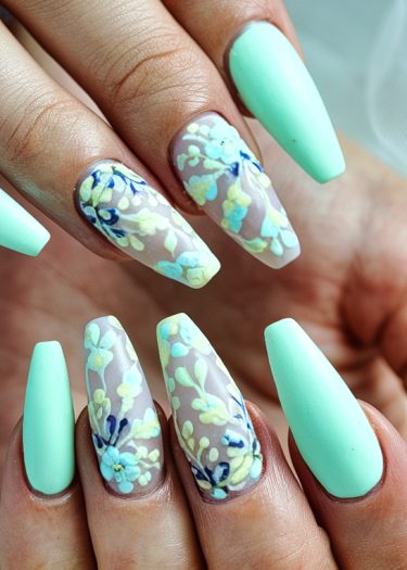 Elegant mint green floral nail art design with intricate blossoms on almond-shaped nails.